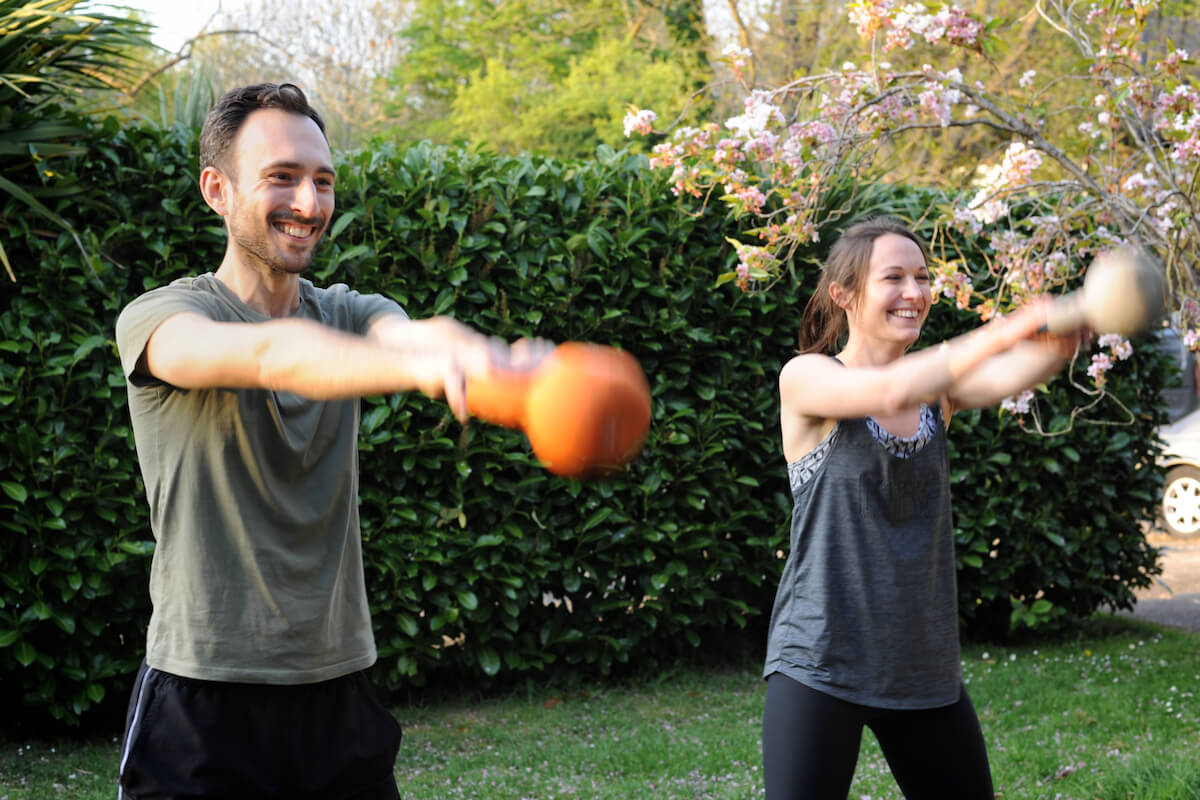 A personal trainer and a client performing a kettlebell swing exercise