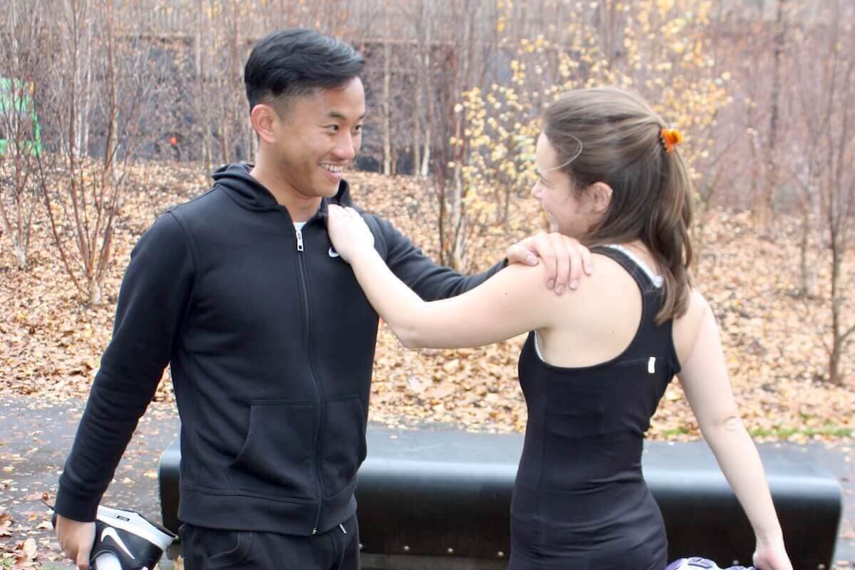 A couple stretching in a park during a personal training session